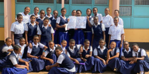 Group of girls holding a sign with a message of thanks for volunteering at the Moshi Tanzania Community School