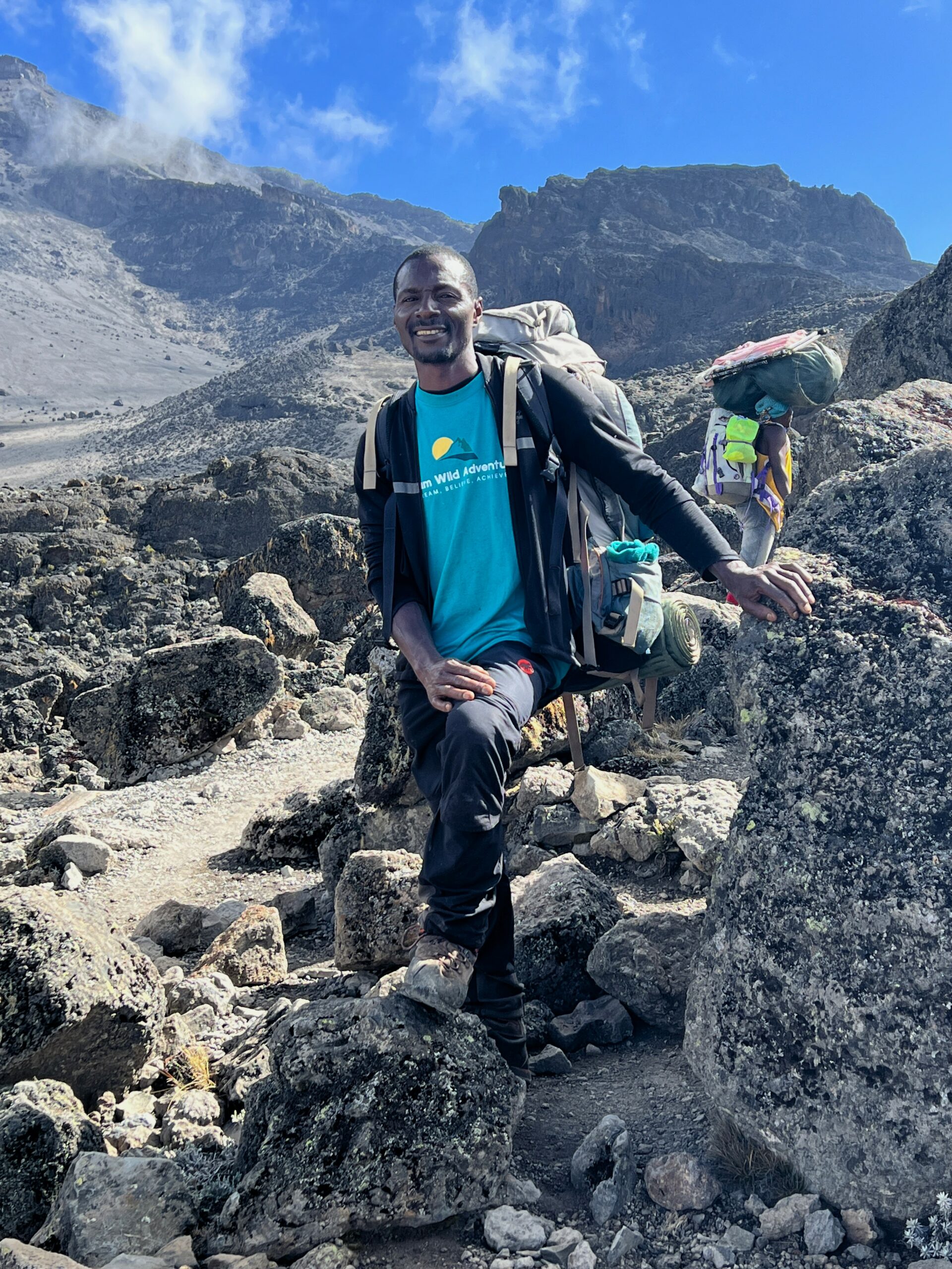 A Kilimanjaro guide sitting on rocks with a backpack