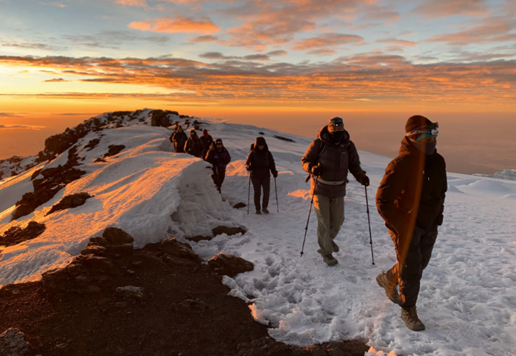 hikers climbing toward the summit of mount kilimanjaro at sunrise